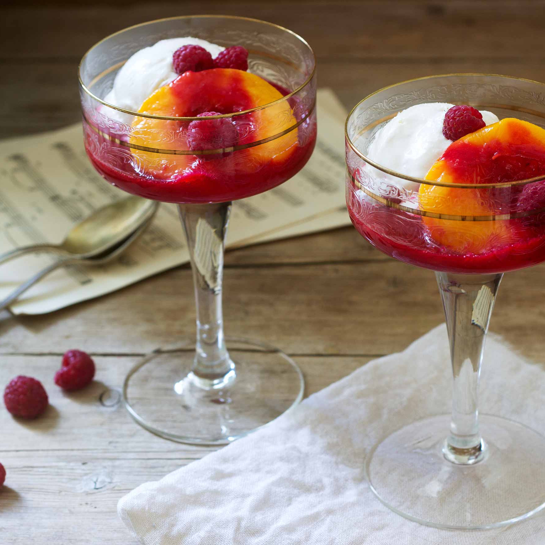 Eisbecher mit Pfirsichen Zwei Gläser mit Fruchtdessert, dekoriert mit Erdbeeren.