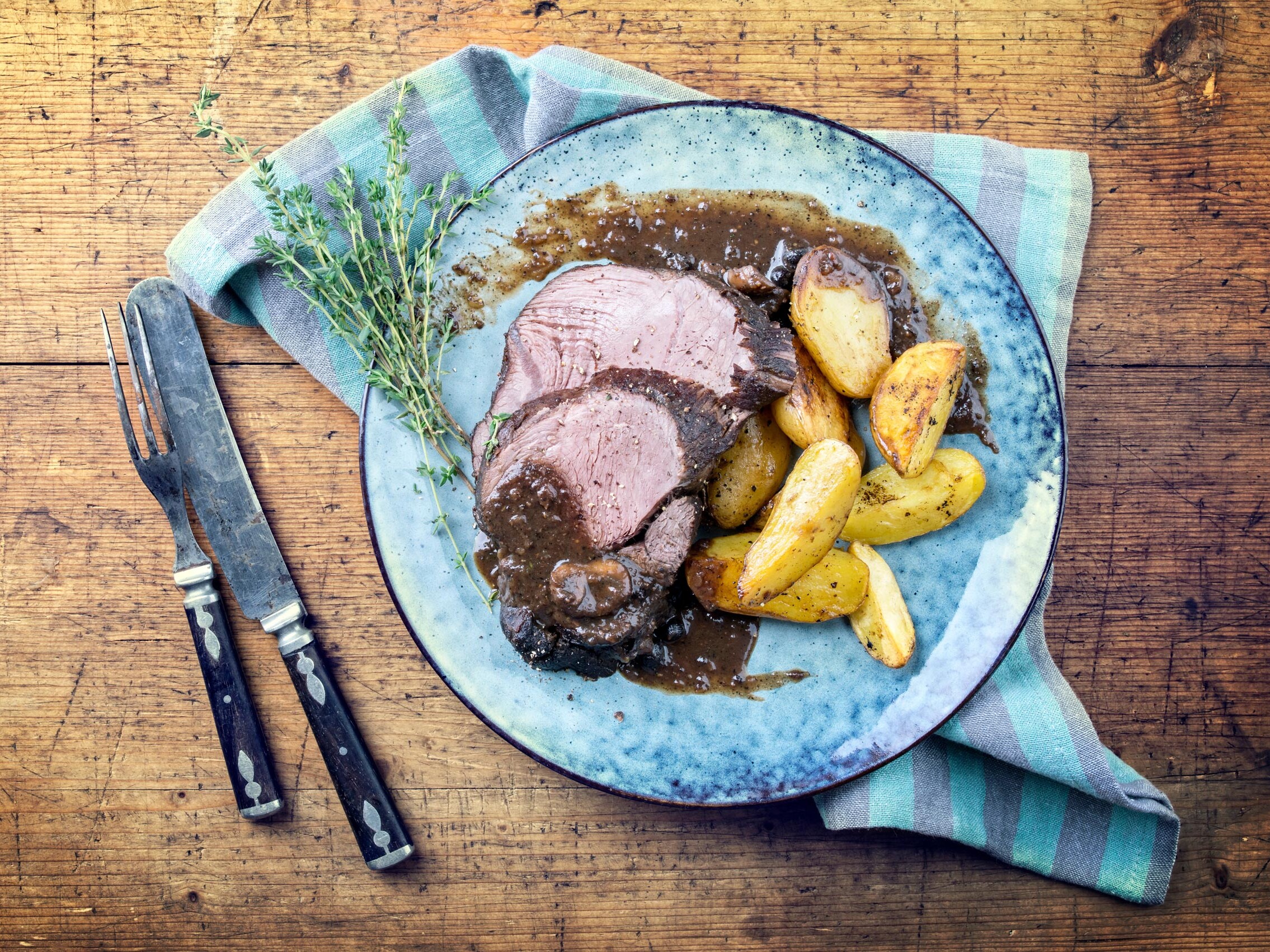 Wildschweinbraten Ein Teller mit Fleisch und Kartoffeln.